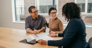 Couple signing documents with an adviser at a table