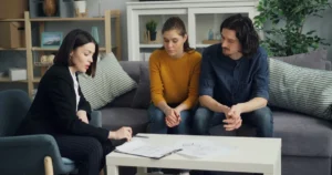 Couple on a sofa while an adviser explains paperwork