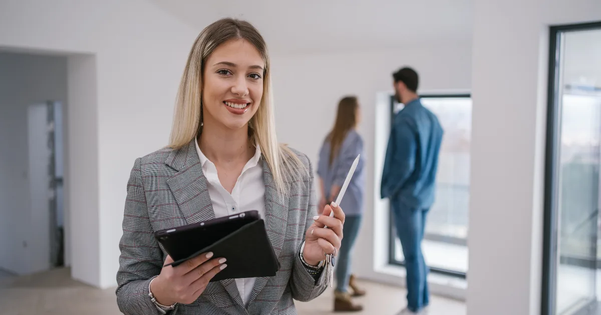 Smiling agent holding a tablet in an empty apartment