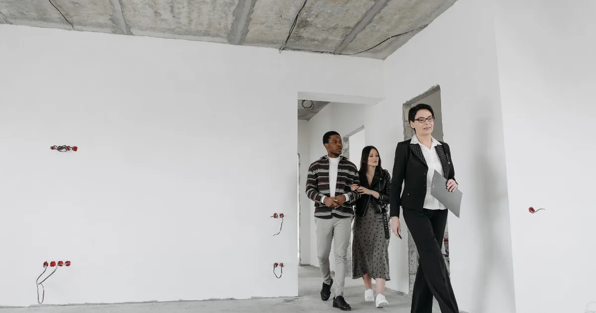 Agent showing a couple through an unfinished apartment