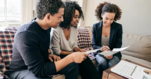 Couple reviewing paperwork with an adviser on a sofa