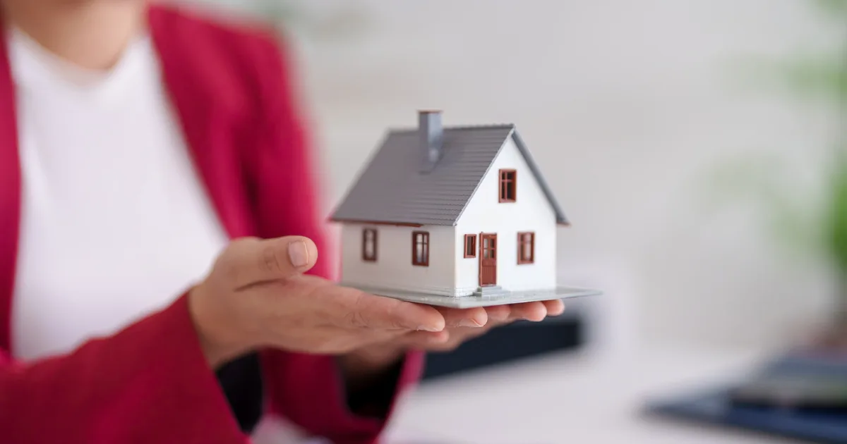 Hands holding a small model house
